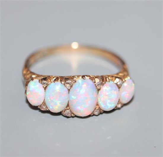 An early 20th century 18ct. gold, graduated five stone white opal and diamond chip half hoop ring, size O.